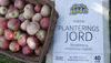 A basket of red apples sits beside a bag of growing soil made from recycled raw materials.