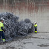 Two Stena Metal Group employees standing beside a large pile of aluminium that is ready for recycling.